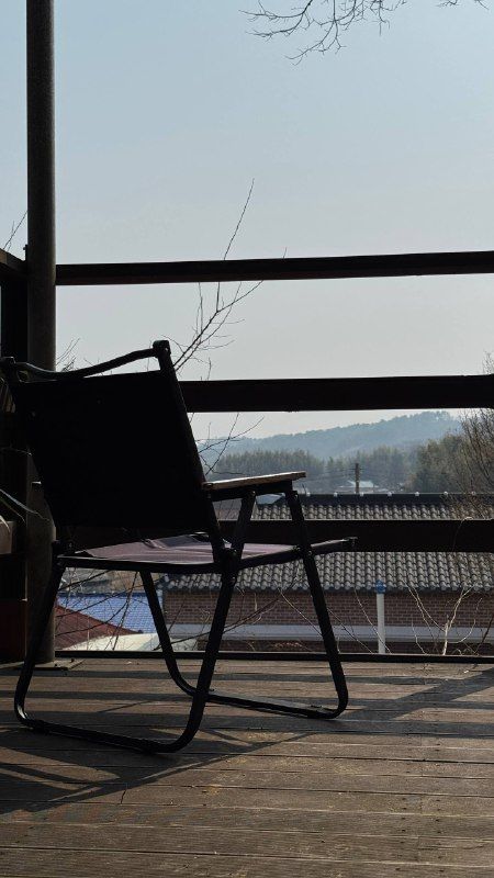 A folding chair on a balcony looking out over rooftops and hills