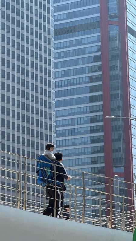 Two people on a footbridge in front of glass office towers