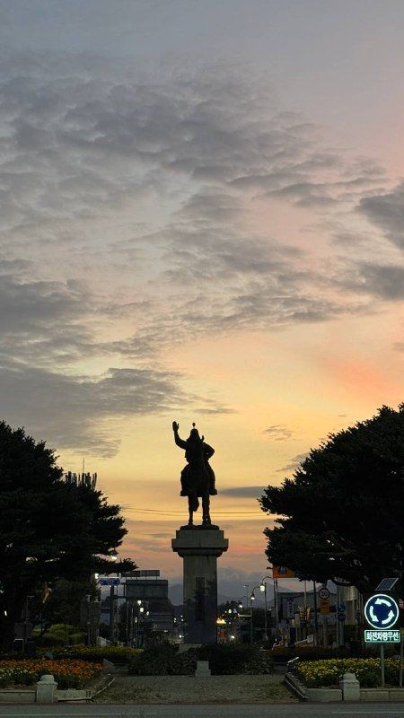 A statue on horseback silhouetted against a glowing dusk sky