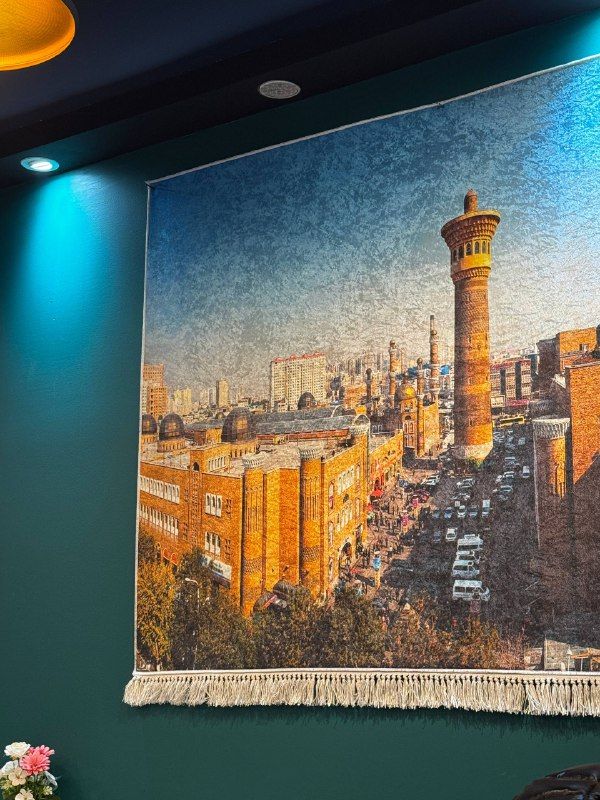 A tapestry of a mosque minaret and city on a teal wall