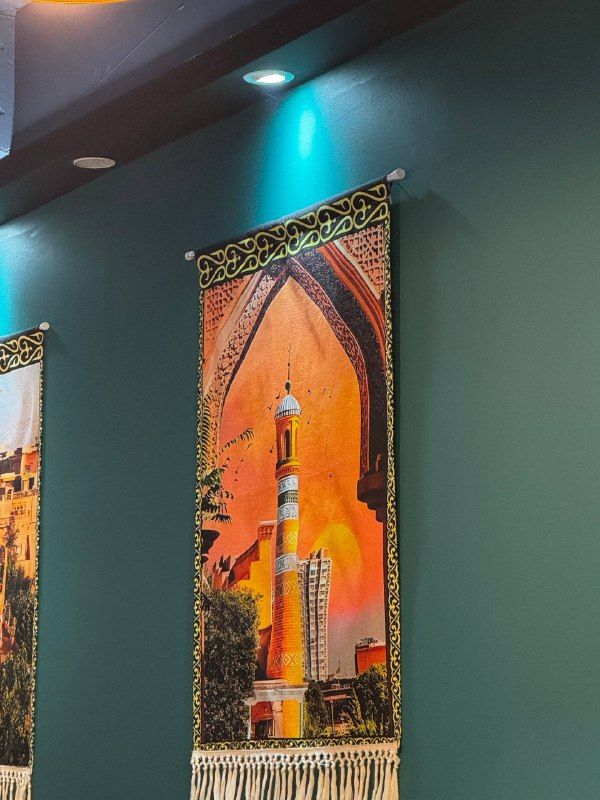 A tapestry of a minaret and arched gateway on a teal wall