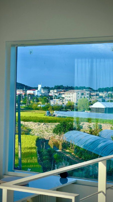 A window looking out over village rooftops and green fields