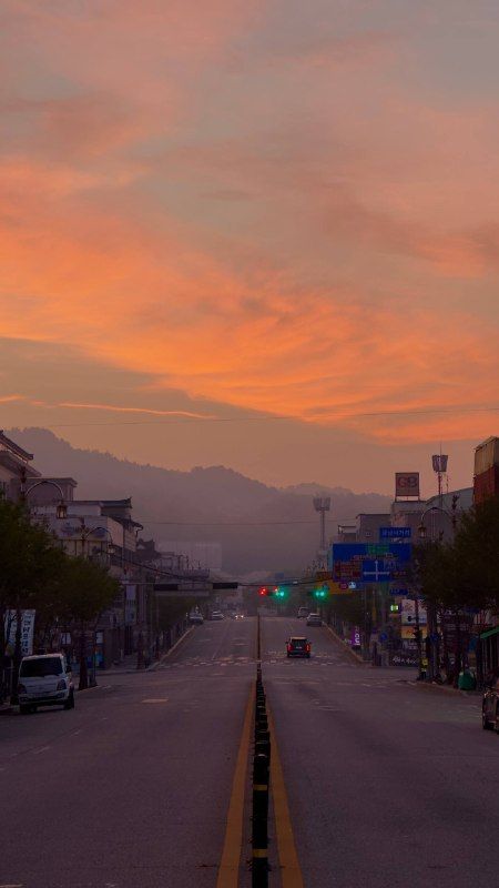 The same main road at dusk, a red sky fading over the mountains